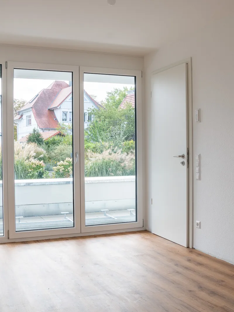 Elternzimmer mit bodentiefer Verglasung zur Dachterrasse und Blick in die Gärten, rechts die Zimmertür