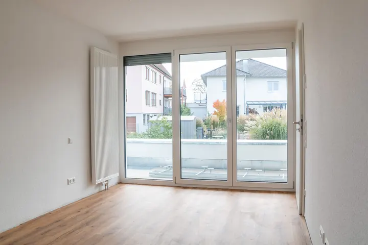 Elternzimmer mit Verglasung zur Dachterrasse, dahinter Nachbarhäuser und Gärten