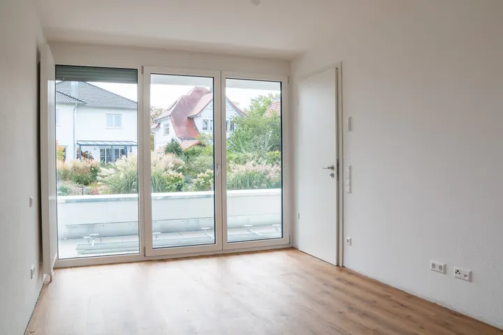 Elternzimmer mit dreiteiliger bodentiefer Verglasung und Blick in grüne Gärten