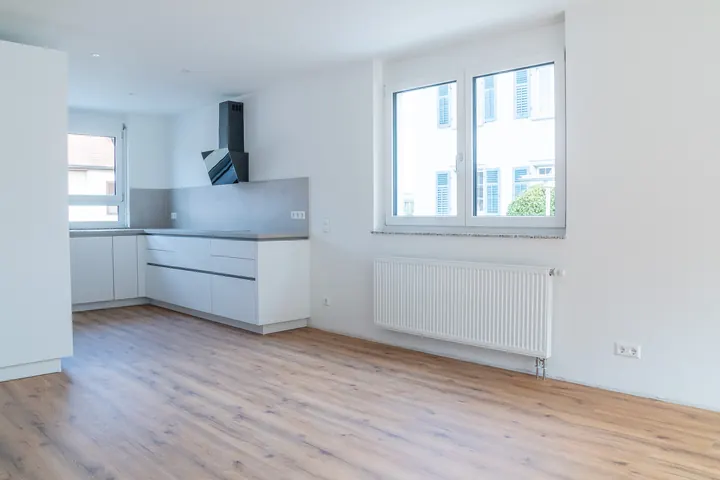 Küchenhalbinsel mit grauer Arbeitsplatte, daneben ein Doppelfenster mit Heizkörper