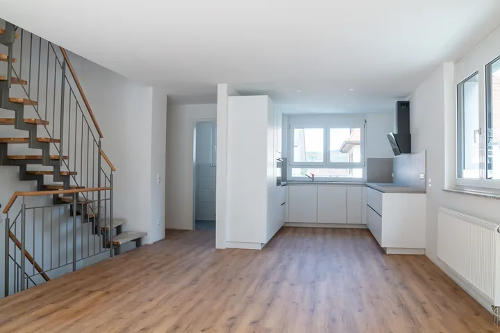 Stahltreppe mit Holzstufen vor der offenen weißen Küche