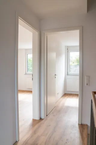 Flur im Obergeschoss mit zwei offenen Türen in helle Zimmer