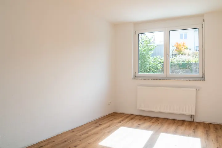 Kinderzimmer mit Doppelfenster ins Grüne und Sonnenlicht auf dem Boden