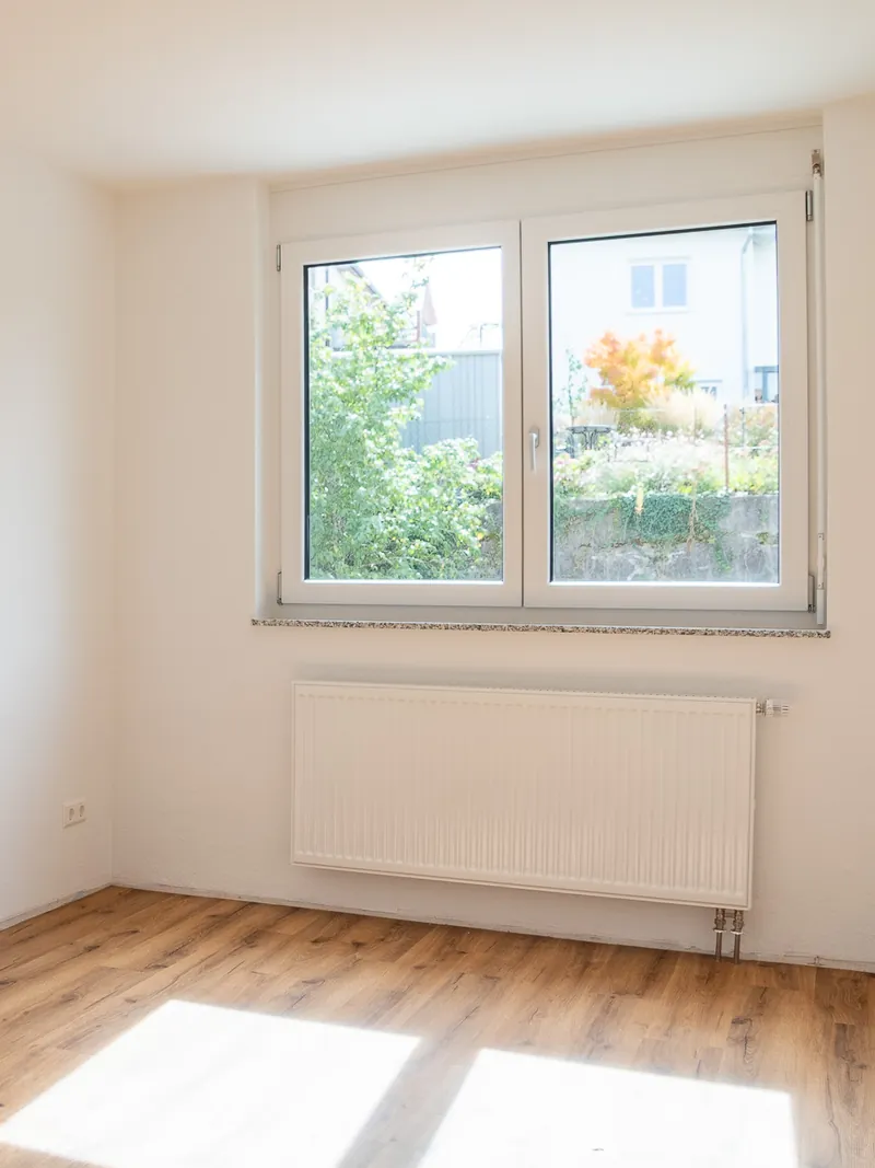 Kinderzimmer zur Gartenseite mit Doppelfenster ins Grüne, Sonnenlicht auf dem Boden