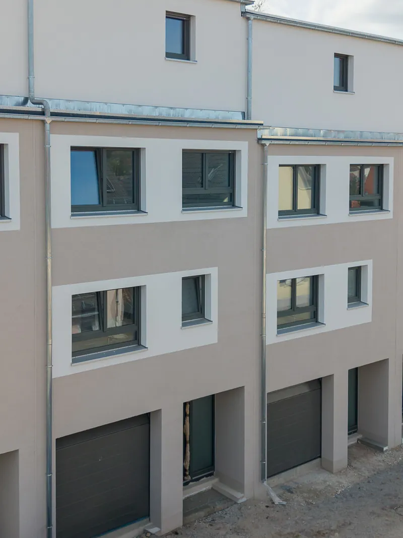Straßenseite der Reihenhäuser mit Garagentoren und Hauseingängen im Untergeschoss